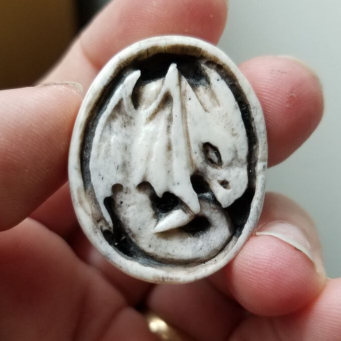 A bone cameo-style carving of a small dragon.